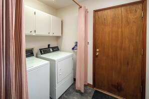 A laundry room with a washing machine, dryer, and a wooden door.