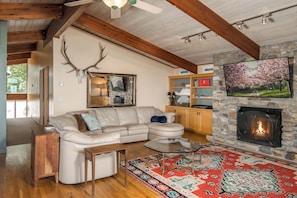 A cozy living room with a stone fireplace, a sectional sofa, and a decorative antler wall piece. - Pet-Friendly 5BR Home! Spectacular Mtn Views, Hot Tub, 5 min to Beech Ski (Beech Mountain)