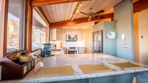 Une cuisine moderne dotée de plans de travail en granit, d’appareils électroménagers en acier inoxydable et de meubles en bois.