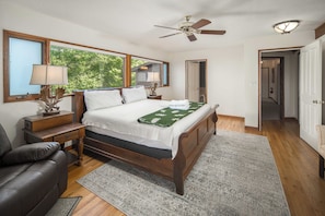 Un dormitorio con una cama de madera, una mesita de noche, una lámpara, una silla y un ventilador de techo.