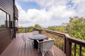 A wooden deck with a round table and two chairs, overlooking a forested area. - Pet-Friendly 5BR Home! Spectacular Mtn Views, Hot Tub, 5 min to Beech Ski (Beech Mountain)