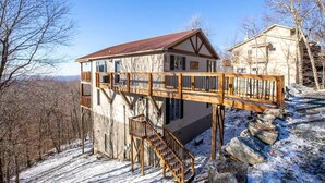 A two-story house with a wooden deck and stairs leading to a balcony. - 5,000ft Peak View Home: Hot Tub, Fire Table & 4 Kings; 5 Min to Resort (Beech Mountain)