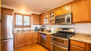A kitchen with wooden cabinets, stainless steel appliances, a granite countertop, and a window with blinds. - 5,000ft Peak View Home: Hot Tub, Fire Table & 4 Kings; 5 Min to Resort (Beech Mountain)