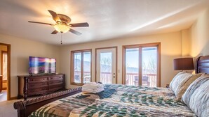 A bedroom with a large bed, a ceiling fan, a dresser, a television, and a balcony with a view. - 5,000ft Peak View Home: Hot Tub, Fire Table & 4 Kings; 5 Min to Resort (Beech Mountain)
