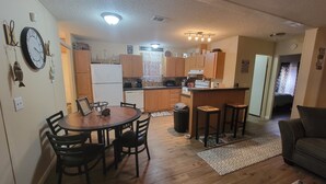 A compact kitchen with wooden cabinets, a dining area with a table and chairs, and a small bar area. - Cozy 3-bedroom, 2 full bath mobile home on half acre in charming Welaka! (Welaka)