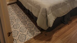A bedroom with a large bed, two wall-mounted lamps, a painting, and a patterned rug. - Cozy 3-bedroom, 2 full bath mobile home on half acre in charming Welaka! (Welaka)