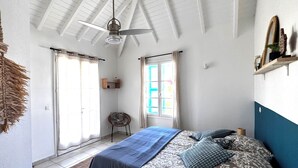 A bedroom with a bed, a ceiling fan, a window, and a door. - Villa Zanoli - a tropical paradise with swimming pool, close to everything! (Appartement)