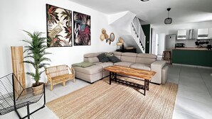 A modern living room with a sofa, a coffee table, and a dining area. - Villa Zanoli - a tropical paradise with swimming pool, close to everything! (Appartement)