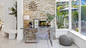 Una sala de estar moderna con pared de piedra, una mesa de centro de vidrio y vista al jardín.