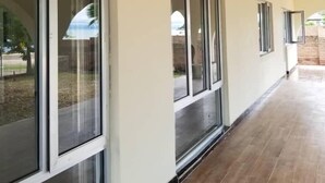 A corridor with large windows, a tiled floor, and a light-colored wall.