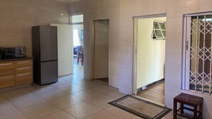 A spacious kitchen with a refrigerator, wooden cabinets, and a tiled floor.
