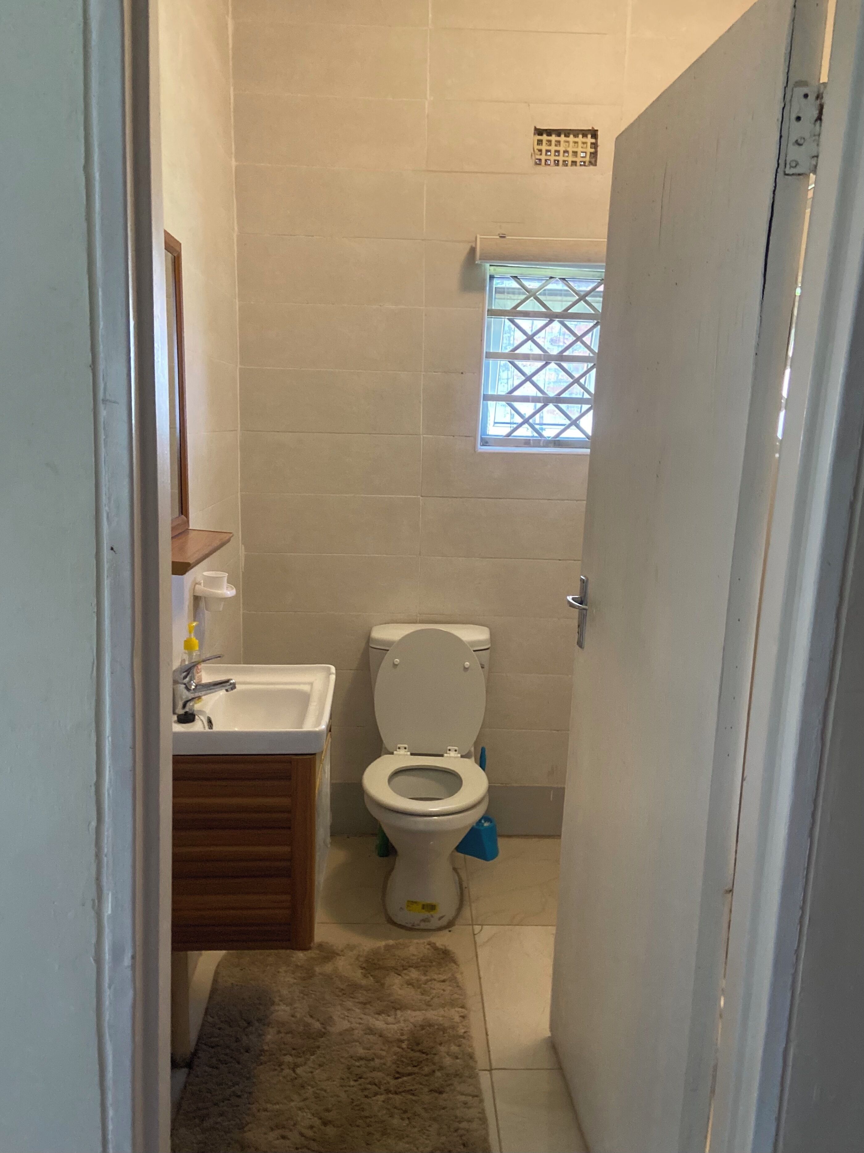 Une petite salle de bain avec des toilettes, un lavabo et une fenêtre.