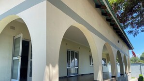 A building with a covered outdoor area featuring a series of arches and a wooden floor.