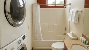 Un baño pequeño con lavadora, inodoro, bañera y lavamanos.