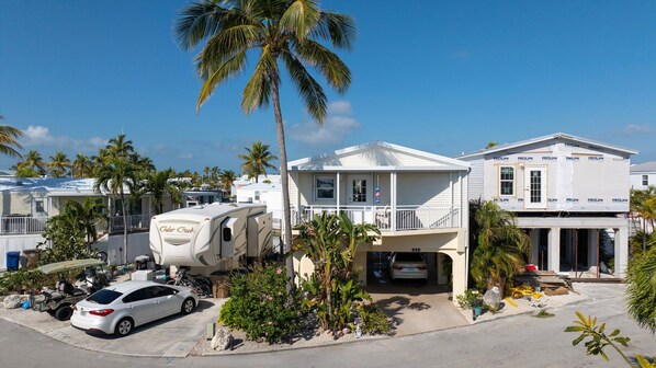 Une maison située sur la côte, dotée d’un porche abrité, avec une voiture garée et une remorque à proximité.