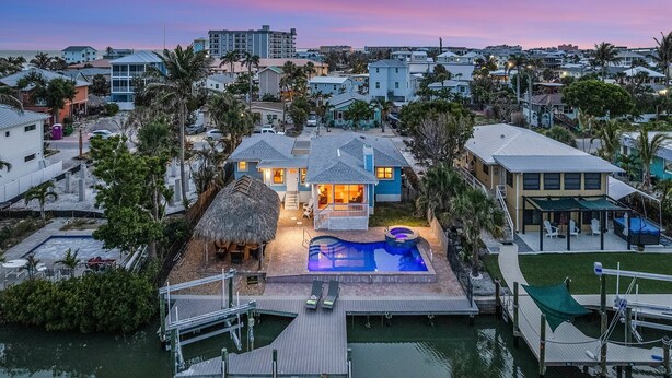 A residential property with a swimming pool, dock, and thatched-roof structure. - Gulf Access, Heated Pool & Spa, Tiki Hut - Roelens (Fort Myers Beach)