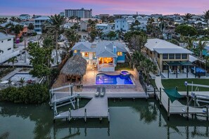 Une propriété résidentielle dotée d’une piscine, d’un quai et d’une structure à toit de chaume.
