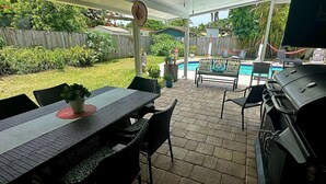 Eine Außenpatio mit Tisch und Stühlen, einem Grill und einem Pool im Hintergrund.