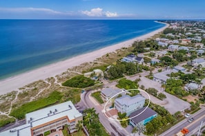 Vista aérea de una zona residencial costera con playa, casas y una carretera.