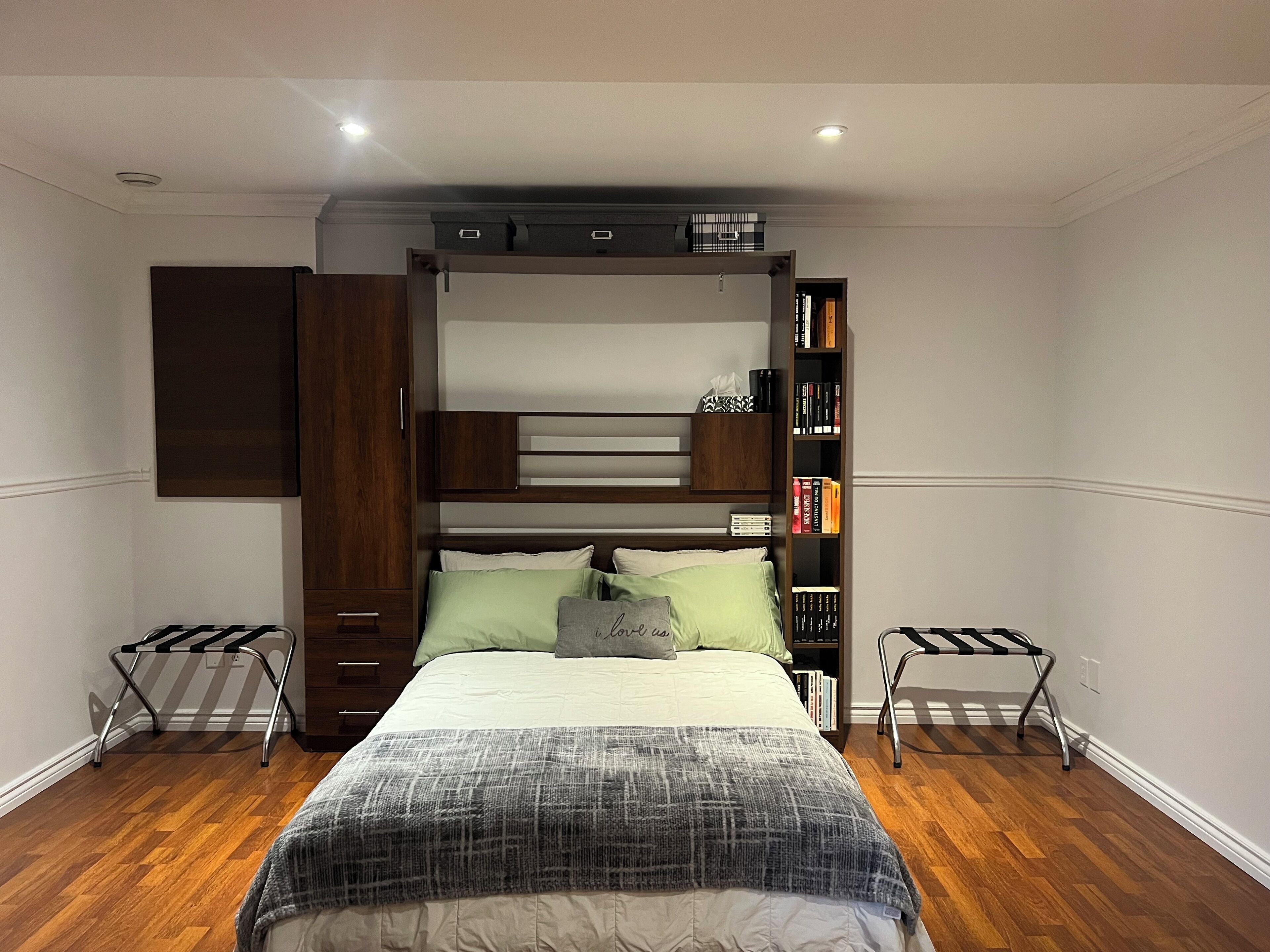 A bedroom with a bunk bed, a bedside table, a bookshelf, and a wardrobe.