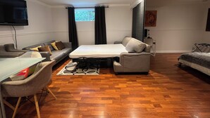 Ett modernt vardagsrum med en soffa, ett litet bord, en säng och en tv som är monterad på väggen.
