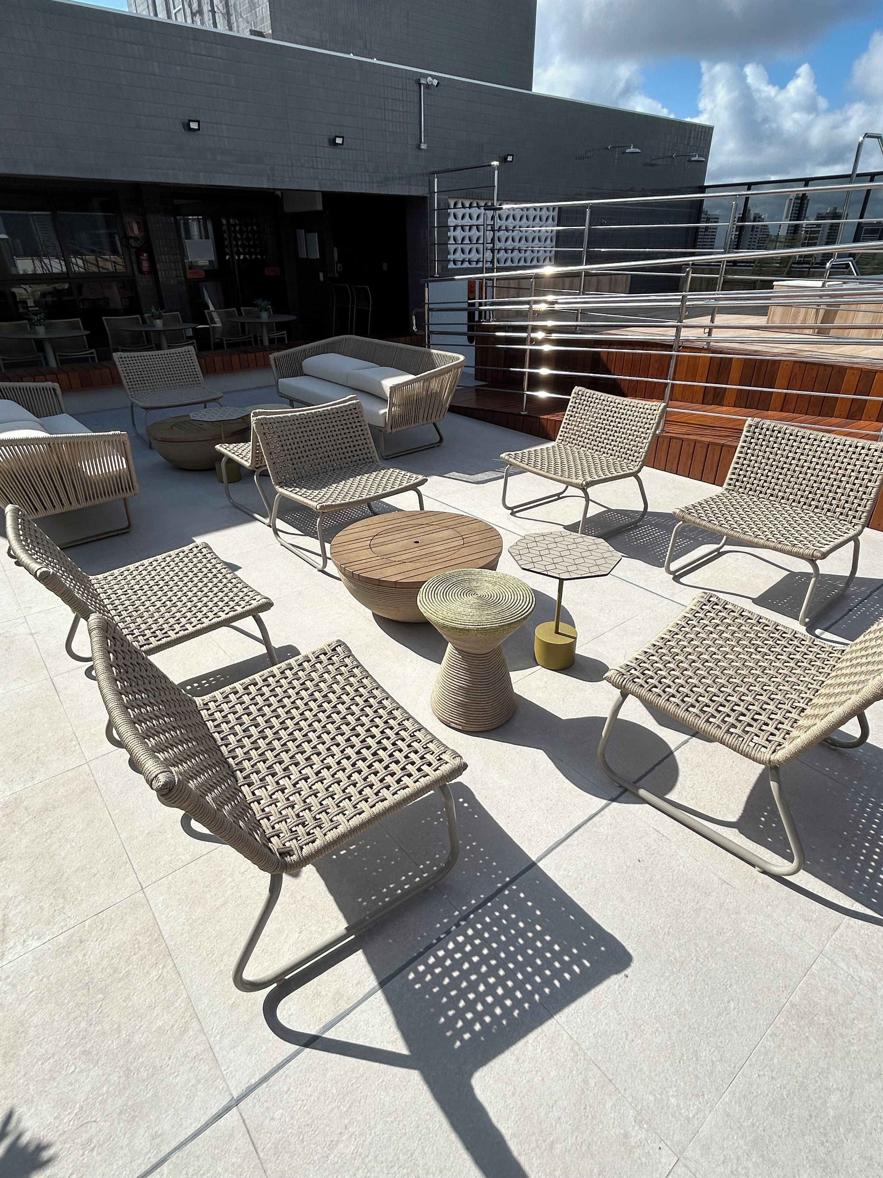 An outdoor seating area with wicker furniture, including chairs and a round table, on a tiled patio.