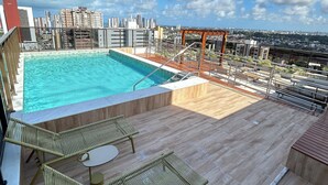 Ein Pool auf dem Dach mit klarem, blauem Wasser, umgeben von Holzterrassen und Metallgeländern.