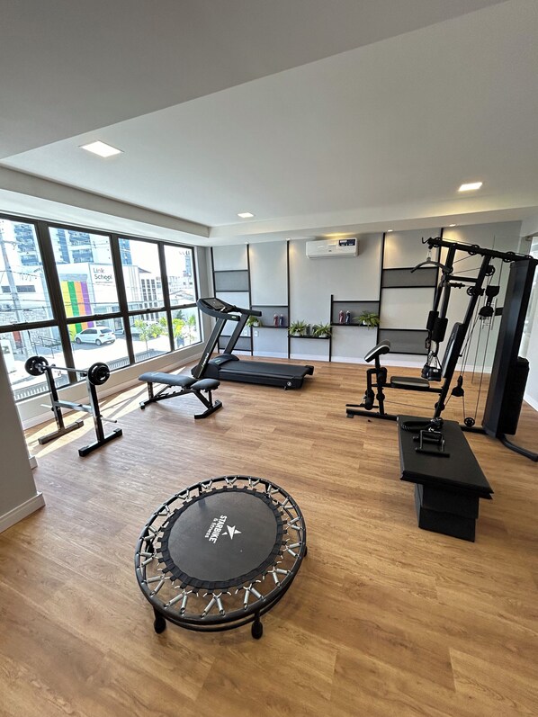 Un gimnasio moderno con trampolín, cintas de correr y máquinas de pesas.
