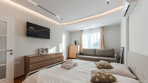 Une chambre moderne avec un lit, un canapé, une télévision et une armoire.