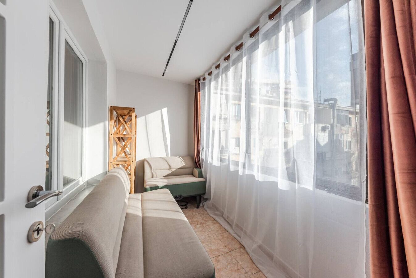 Un salon moderne avec un canapé, une petite table et des rideaux légers.