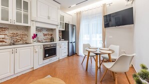 Une cuisine moderne avec des meubles blancs, un mur de fond en briques et un coin repas comprenant une table et des chaises.