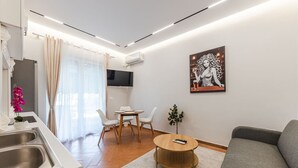 Un salon moderne avec un canapé gris, une table basse en bois et un téléviseur fixé au mur.