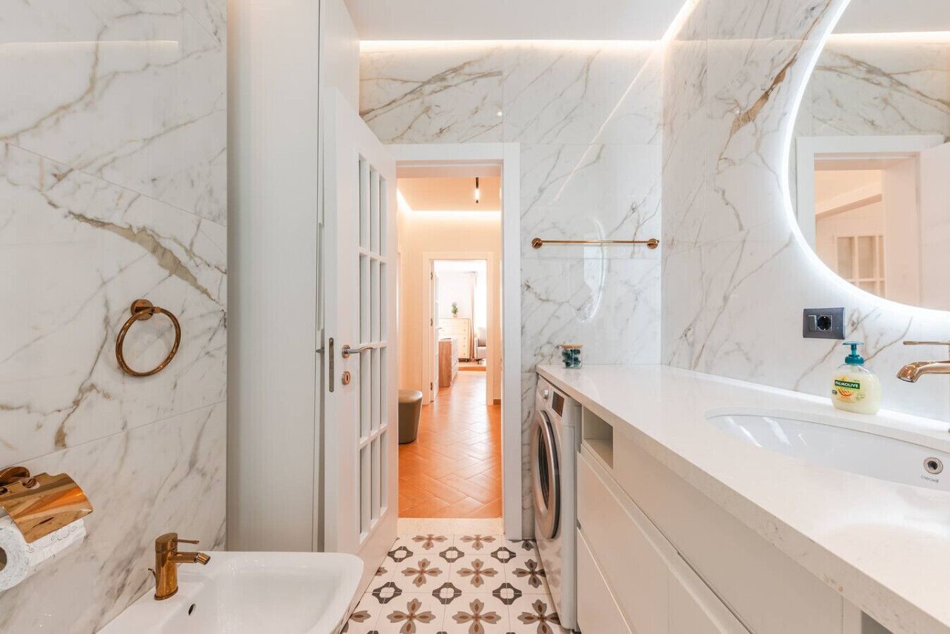 Ein modernes Badezimmer mit Marmorboden, Waschbecken, Toilette und Waschmaschine.