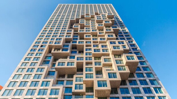 Un immeuble moderne et imposant, doté d’une façade géométrique originale et de nombreuses fenêtres.