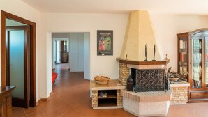 A living room with a fireplace, a bookshelf, and a door leading to another room.