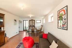 A living room with a sofa, red bean bag, dining table, chairs, and a cabinet. - Villa Francesca - Fermo, wonderful villa in the Marche hills (Petritoli)