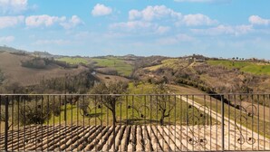 A rural landscape with rolling hills, a clear sky, and a metal fence in the foreground.
