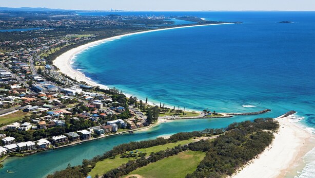 An aerial view of a coastal town with a beach, clear blue waters, and residential buildings. - Cozy Pet Friendly Beach House (Kingscliff)