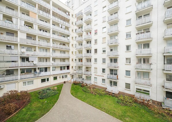 Un edificio residencial de varios pisos con balcones, un patio central y un sendero pavimentado.