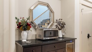 A kitchen with a microwave, a vase with flowers, and a cabinet. - The Townsman: Secretariat Room (Charlottesville)