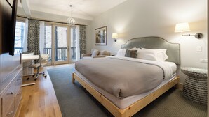 A modern hotel room with a large bed, a desk, and a view of the outdoors. - The Townsman: Meriwether Room (Charlottesville)