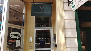 A storefront with a sign for 'The Townsman' hotel, including its address and a 'Closed' sign for a comic book store. - The Townsman: Meriwether Room (Charlottesville)