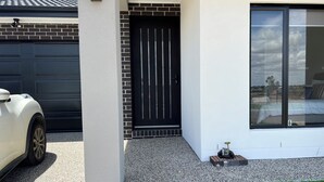 A modern house with a black door, a garage, and a large window. - 4-bedroom Family home /WFH vacation living in Tarneit, West Melbourne (Tarneit)