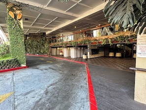 Un'ampia hall con pavimento a scacchi, una linea rossa che indica un percorso e una parete decorata con piante e un pilastro in legno con due racchette.