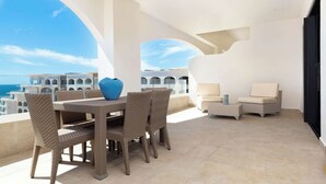 A balcony with wicker furniture, a blue vase, and a view of the sea and buildings. - NEW! Chic resort in perfect San José del Cabo with fitness room (San José del Cabo)