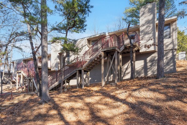 A multi-story building with external staircases and railings, surrounded by trees.
