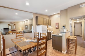 Una cocina moderna con armarios de madera, una isla central y un comedor con mesa y sillas de madera.