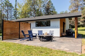 Eine moderne Außenpatio mit Feuerstelle, Sitzgelegenheiten und Grillplatz.