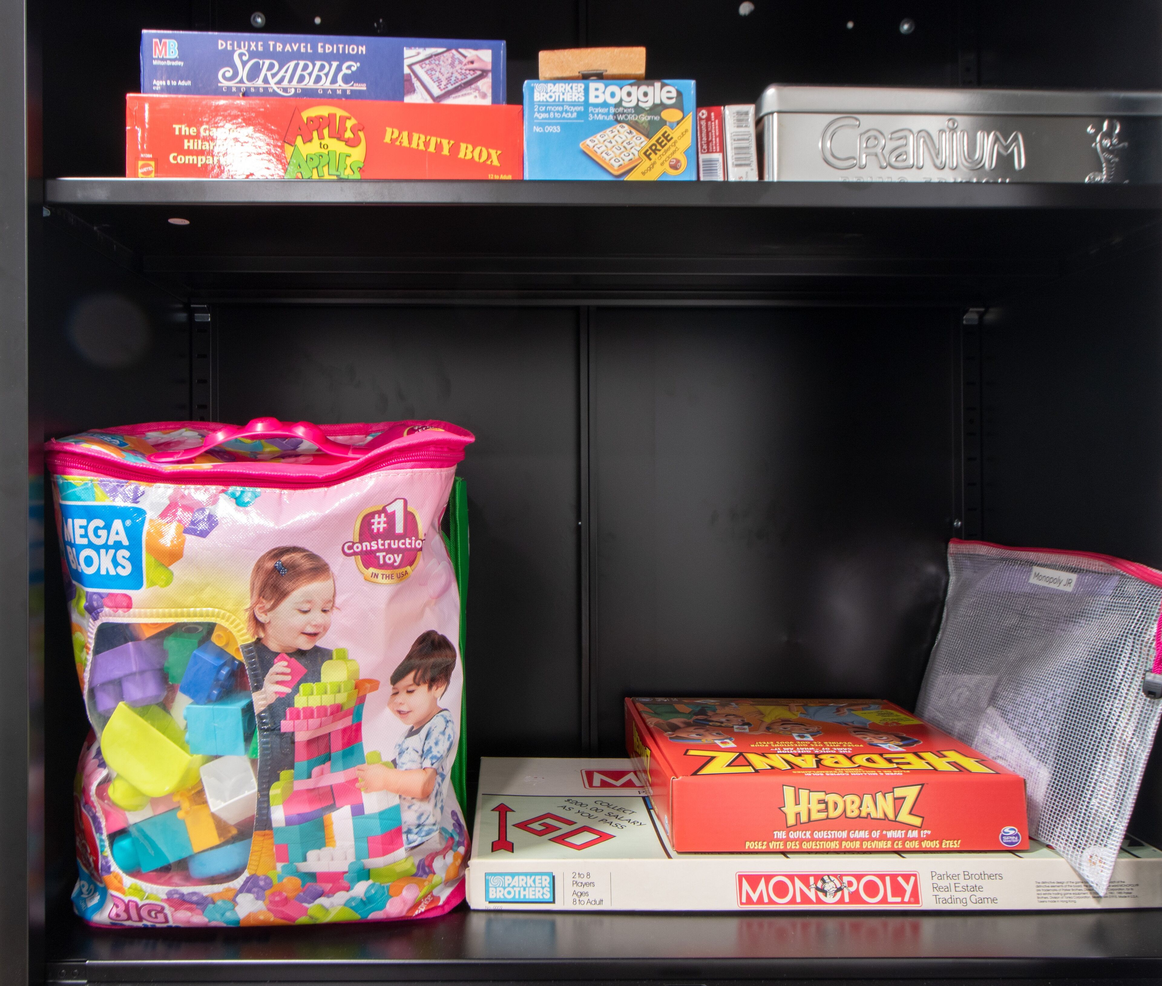 Uma prateleira com diversos jogos de tabuleiro, incluindo Scrabble, Boggle e Monopoly.