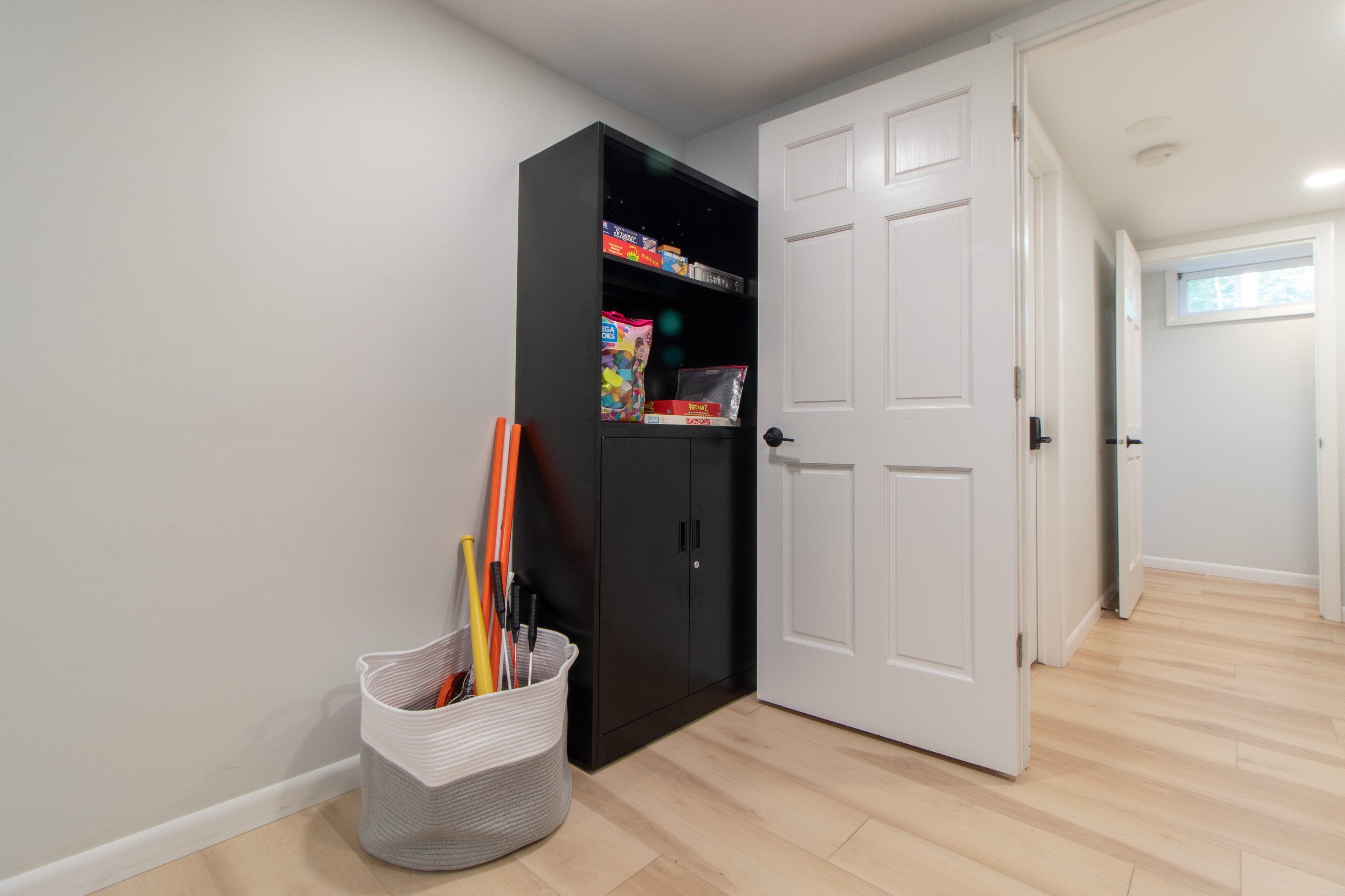 A hallway with a black wardrobe, a basket with items, and a white door.